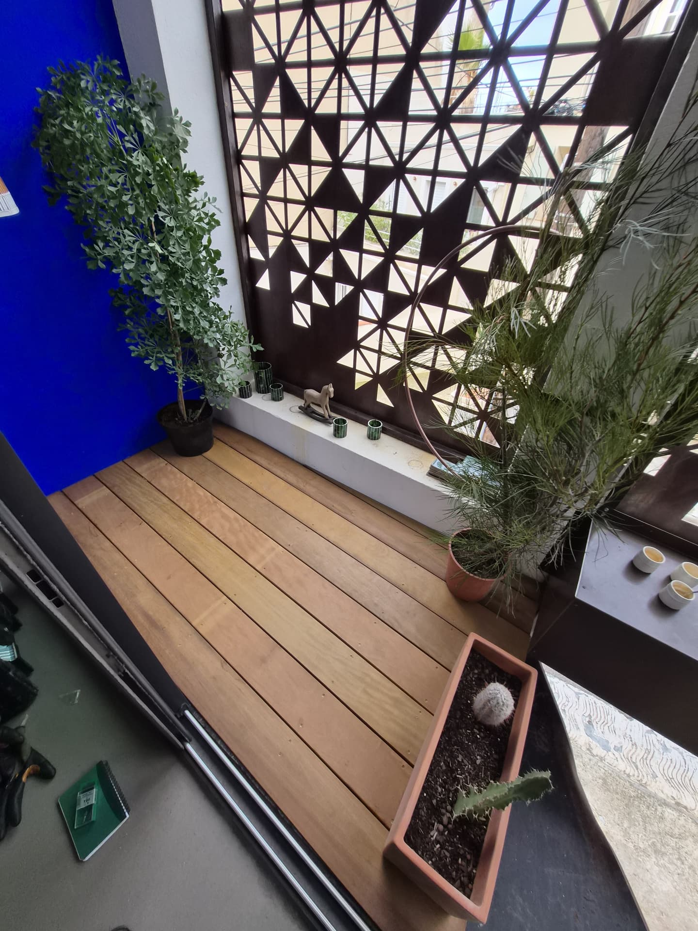 Balcon en lames bois devant un claustra métallique géométrique