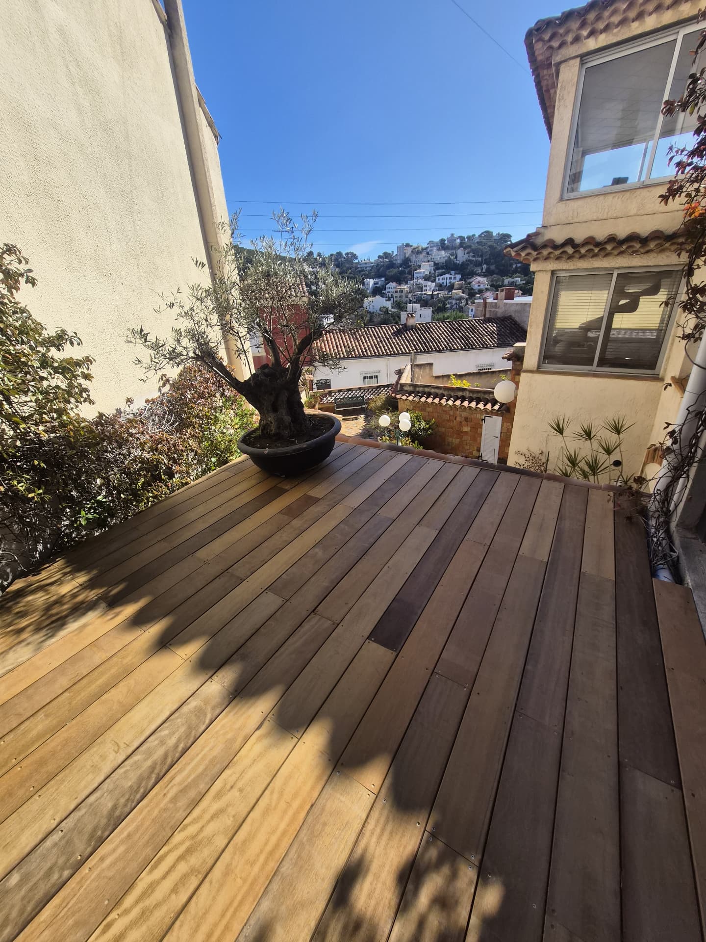 Terrasse bois avec olivier en pot et vue sur les collines