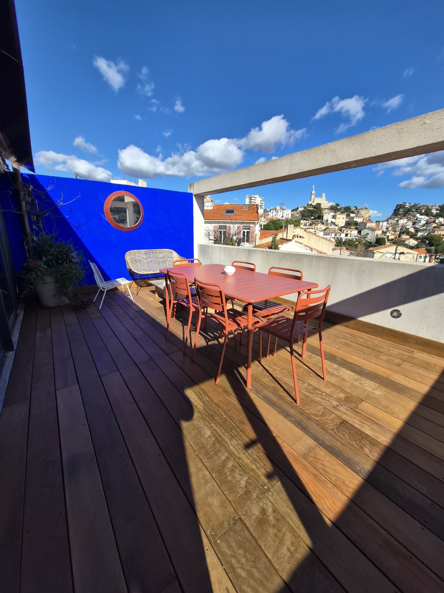 Terrasse bois et mur bleu sur les toits